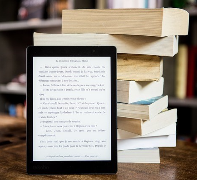 ebook on tablet leaning against pile of books