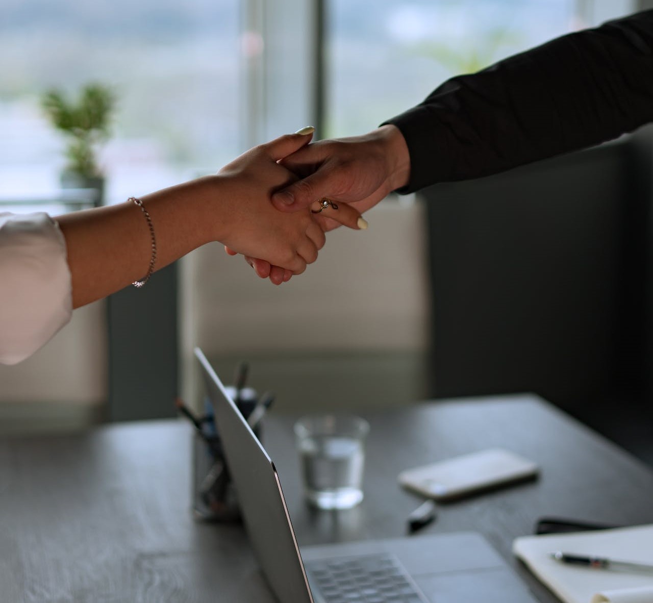 two people shaking hands across a desk