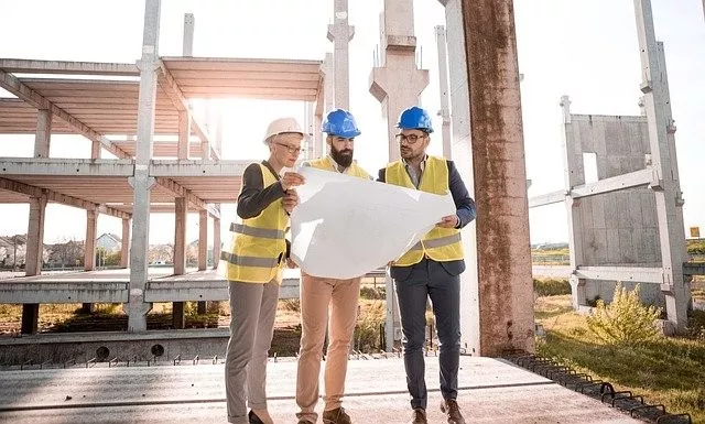 three construction professionals looking at site plans on a building site
